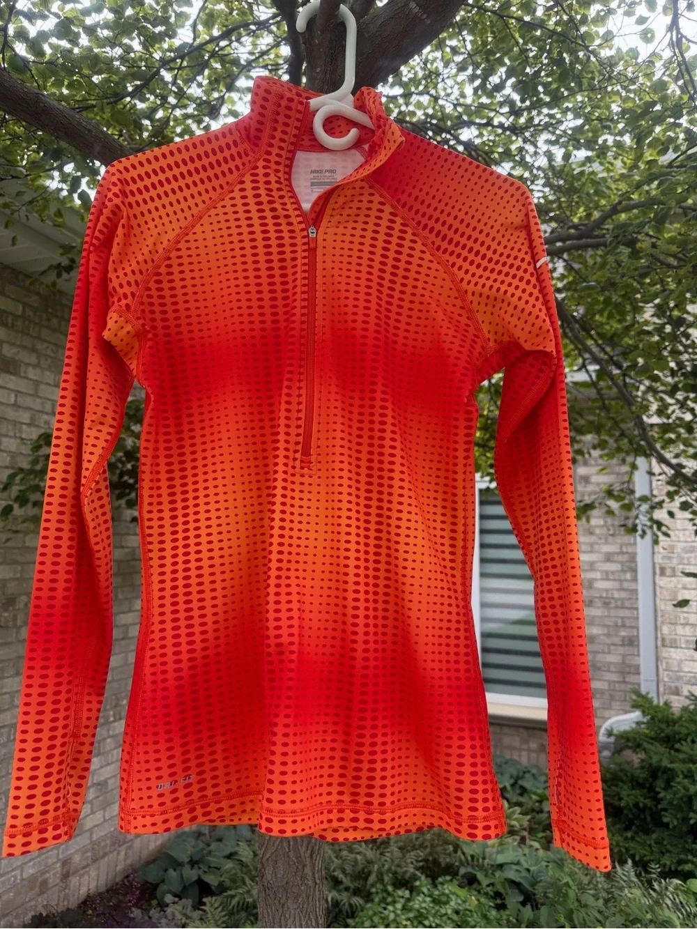 The Nike Pro Hyperwarm half-zip running top features a vibrant orange and red